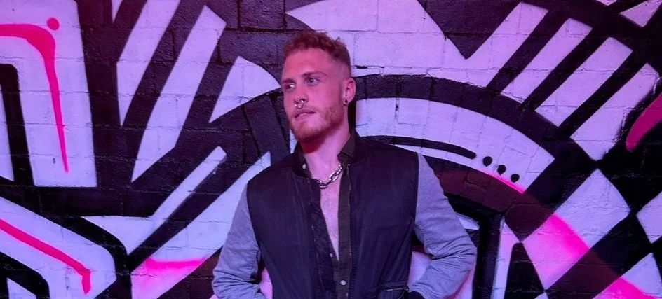 Jake Devline Reed leans against a graffiti-covered wall