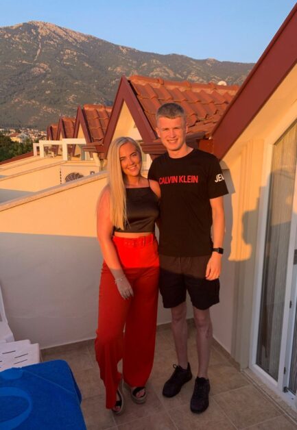 Abbie and Kieran standing on balcony in the sunshine on holiday