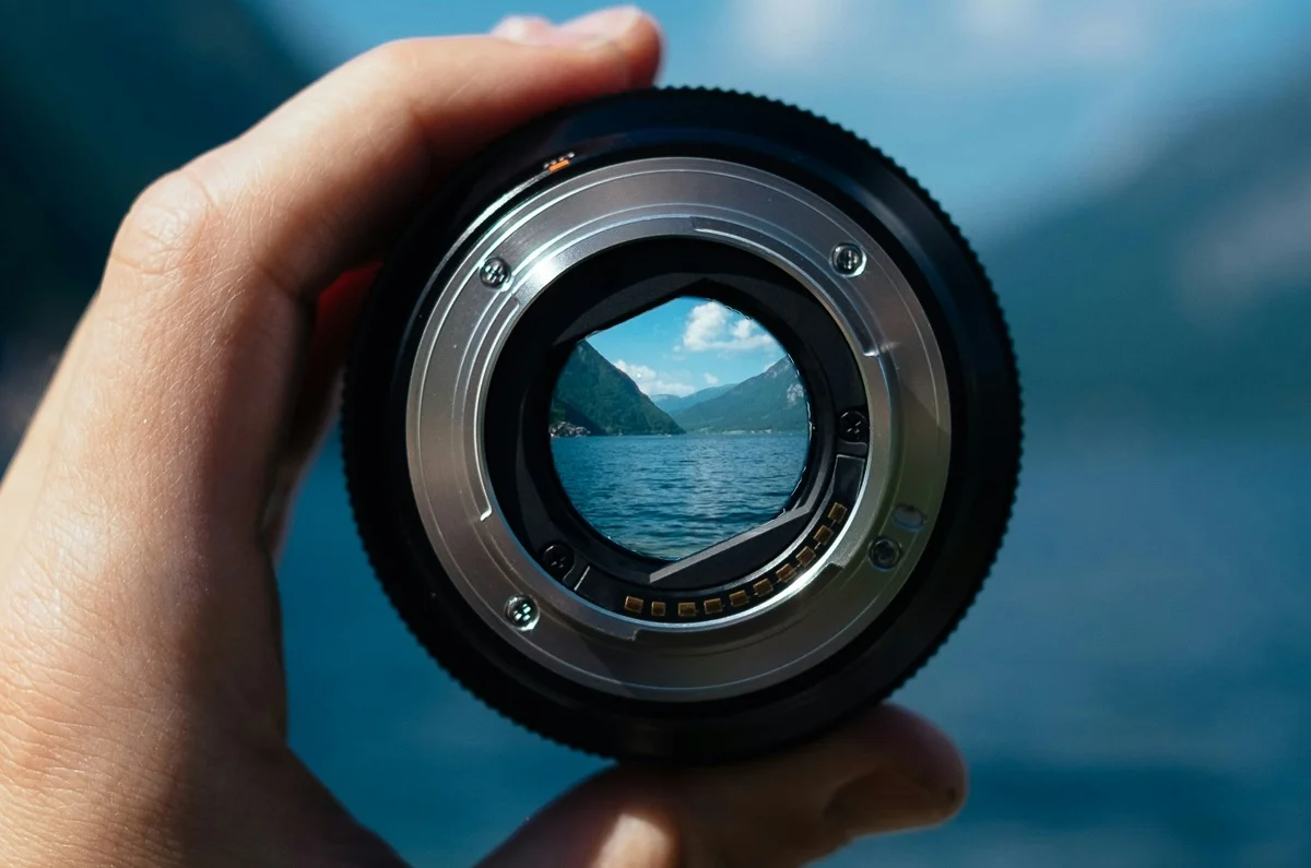 A hand holding a camera lens, with the distance in focus - representing the focused aims of the National Cancer Plan