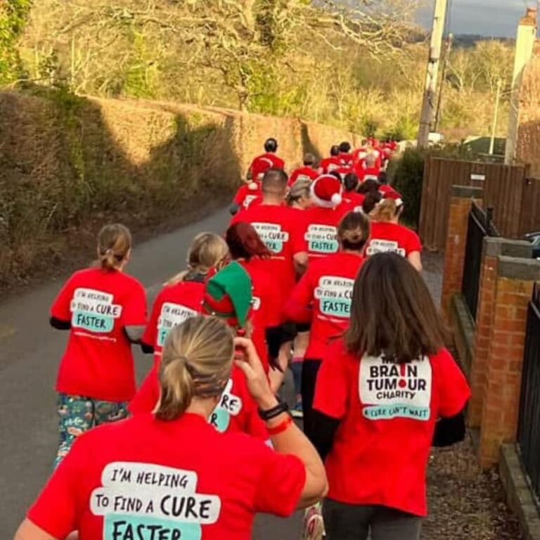 A row of runners wearing red, taking part in festive fundraising for the TCS London Marathon