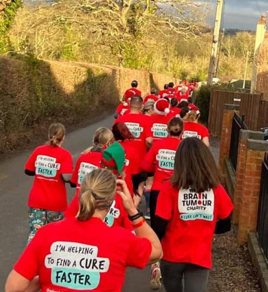 A row of runners wearing red, taking part in festive fundraising for the TCS London Marathon