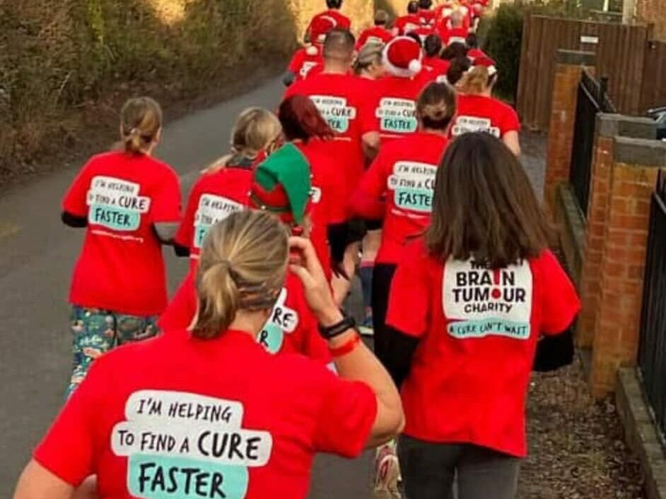 A row of runners wearing red, taking part in festive fundraising for the TCS London Marathon