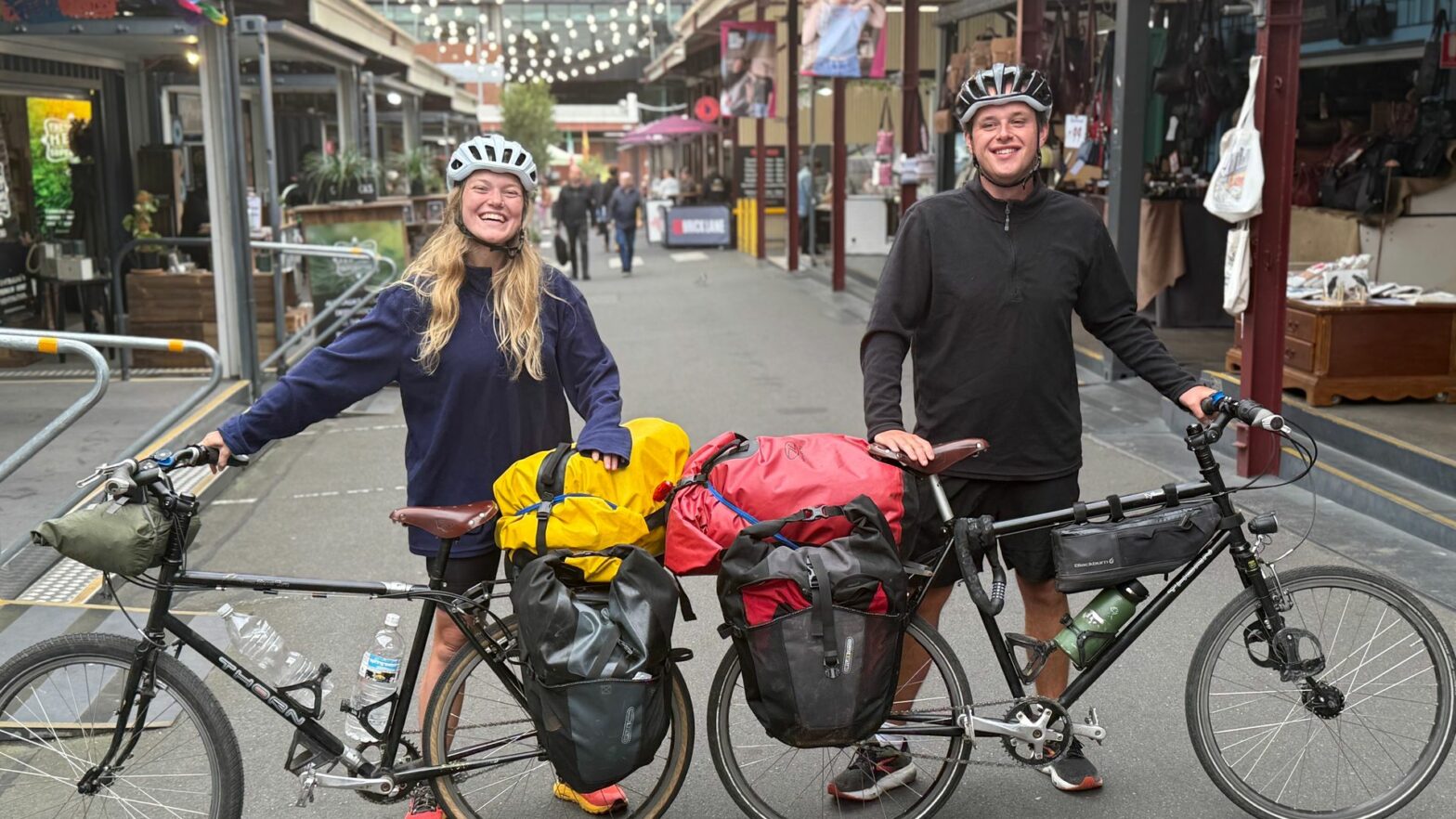 Jeremy and Lottie stand with their bicycles in a street. They'll be cycling from Australia to UK for charity