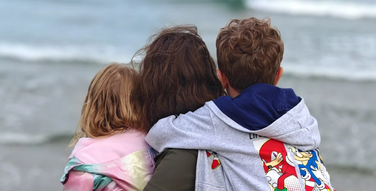 Nikita and her family sit close on the beach, looking at the ocean