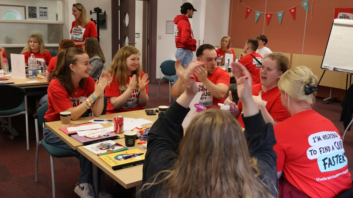 Young Ambassadors sit at a table and clap during the Big Weekend