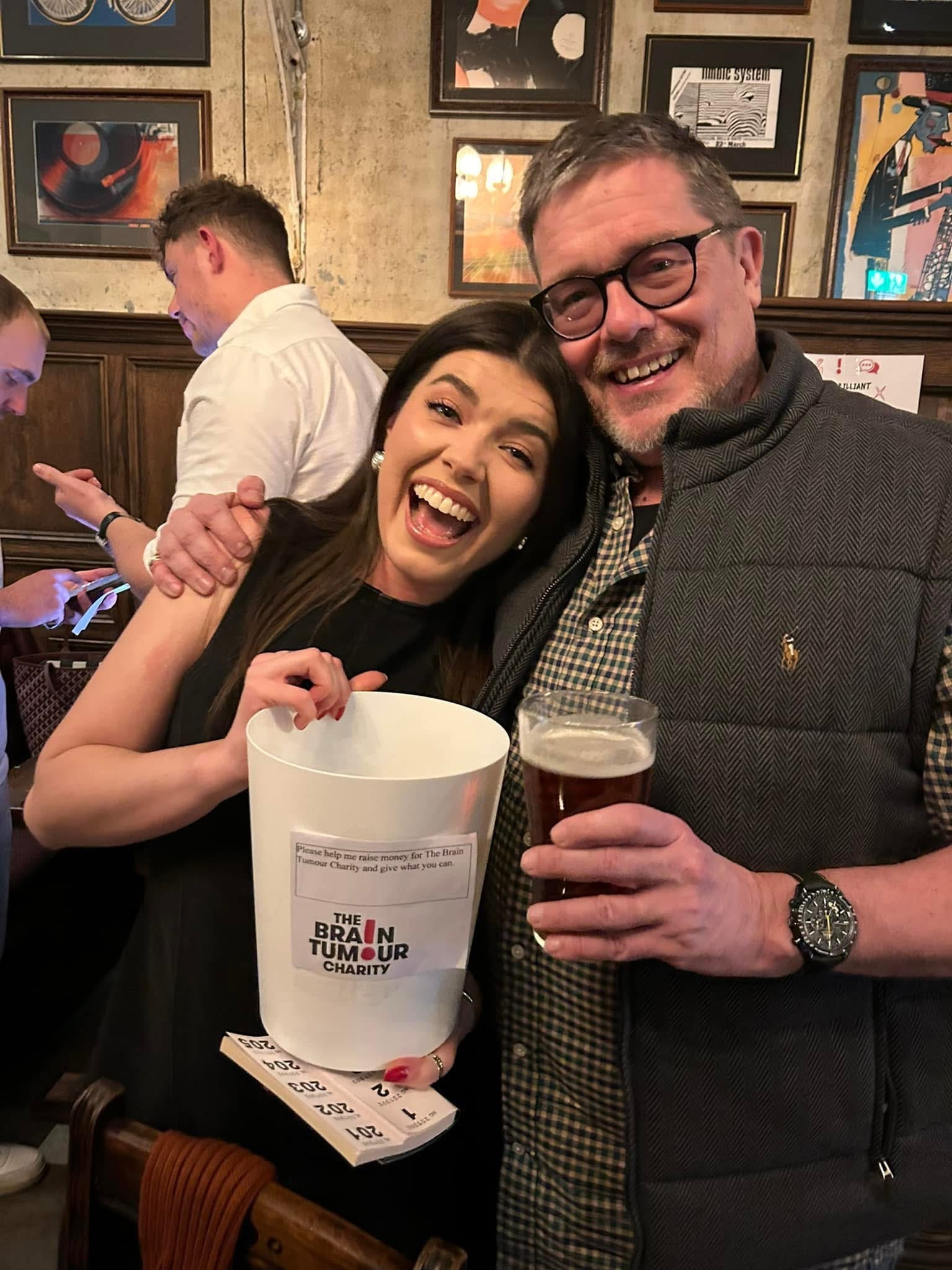 Ellie Smith and her dad holding a collection bucket for The Brain Tumour Charity. Ellie arranged a sculpture auction to help accelerate cures for brain tumours.