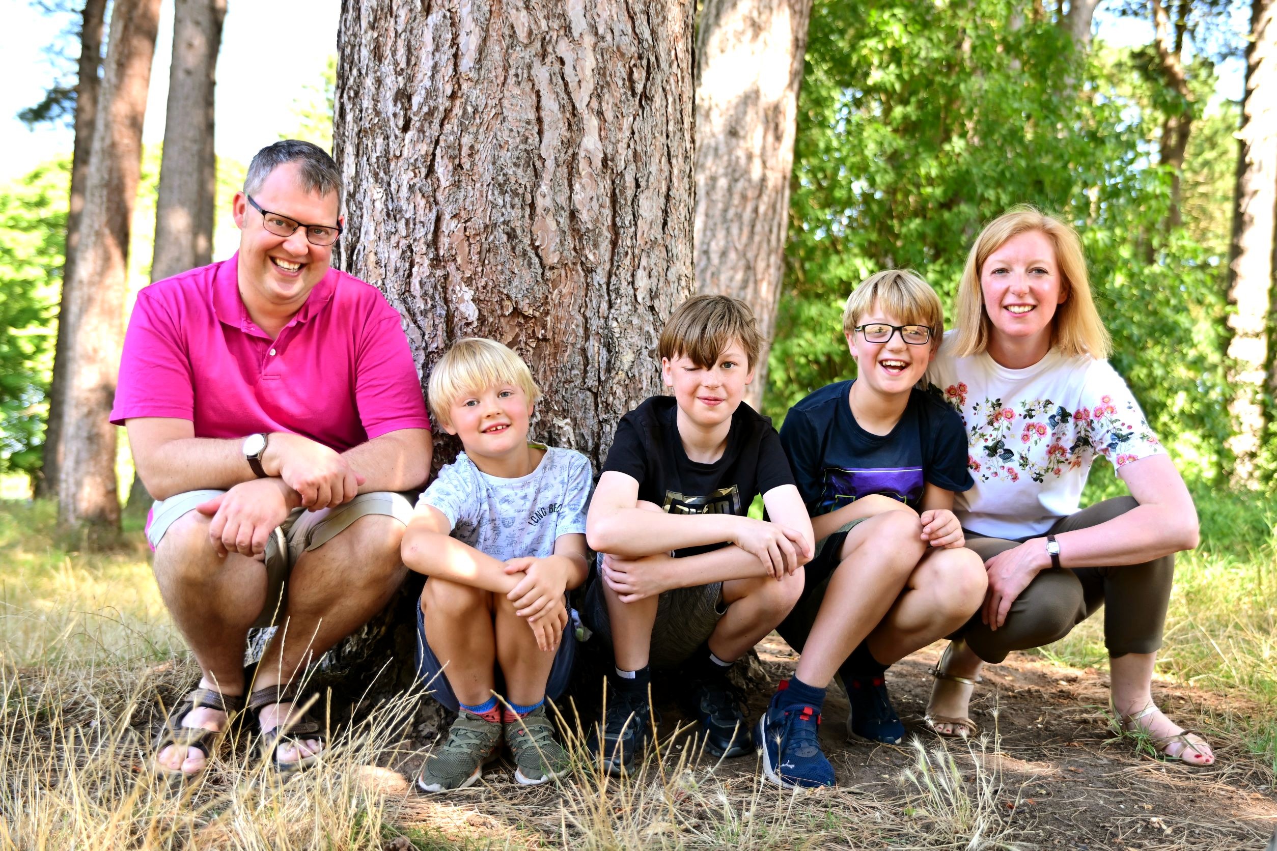 Ted, Becca, and their three sons sit in front of a tree.