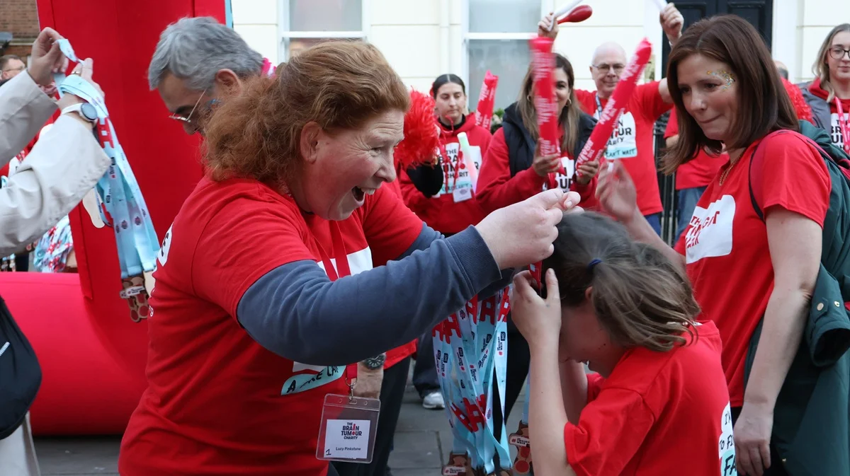 A woman presents a medal to a young girl at the finish of The Twilight Walk