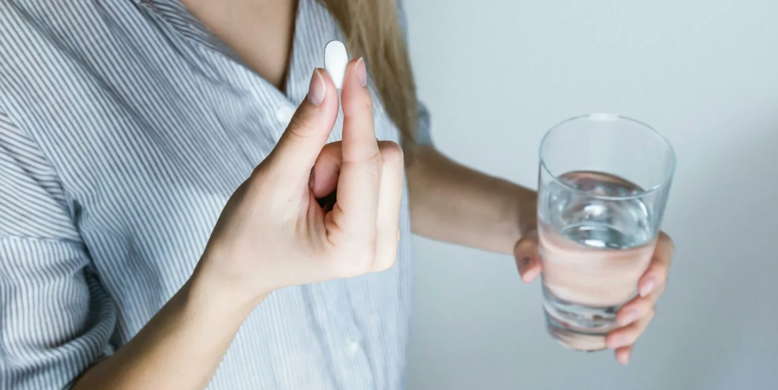 A woman holding a voresidenib pill and a glass of water