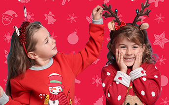 Two young girls wearing red Christmas jumpers for The Brain Tumour Charity's Wear it Red fundraising day in December