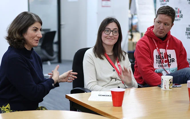 Three people sitting at a table while The Brain Tumour Charity Involvement Network talks with SLT
