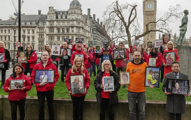A group of people holding photos of lost loved ones during The Brain Tumour Charity campaign launch outside Parliament