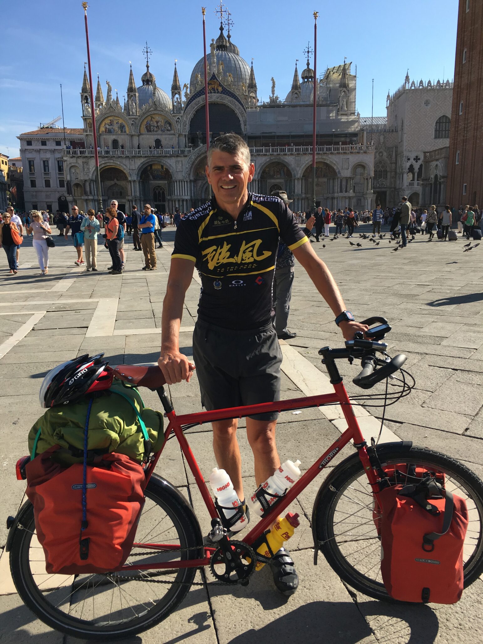 Mark stands with his bicycle in front of a palace