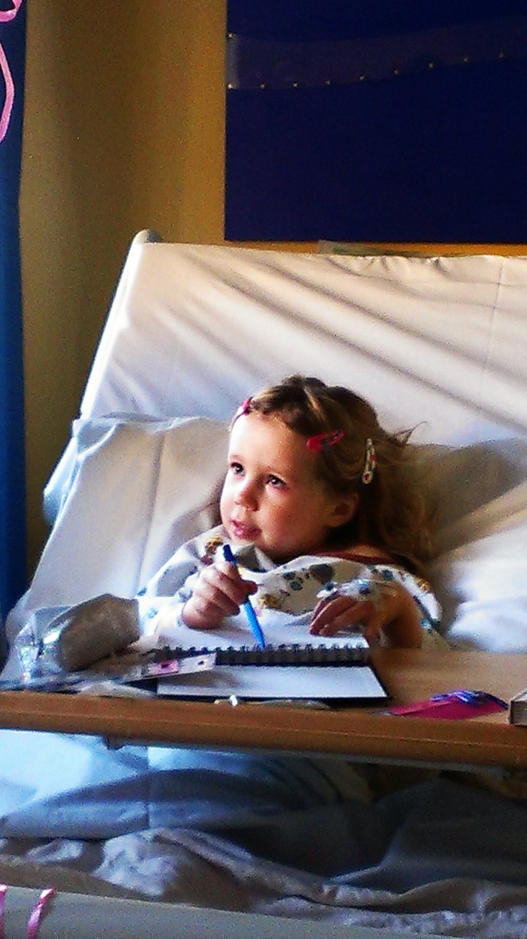 Lily in a hospital bed drawing in a notepad