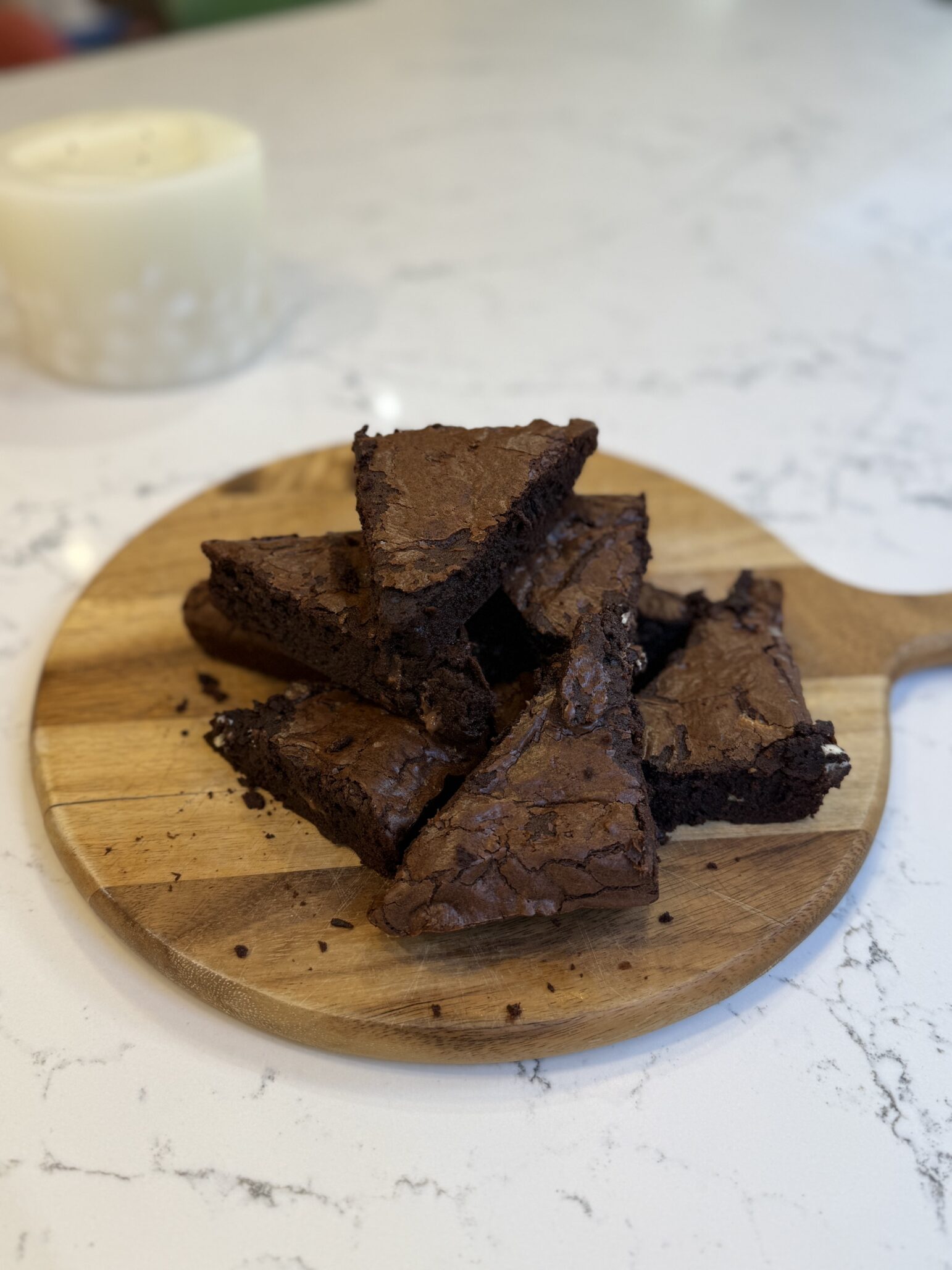 A cluster of chocolate brownies on a wooden serving plate
