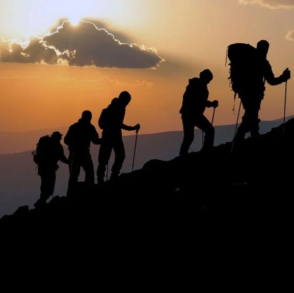 Silhouettes of people climbing Snowdon as the sun sets