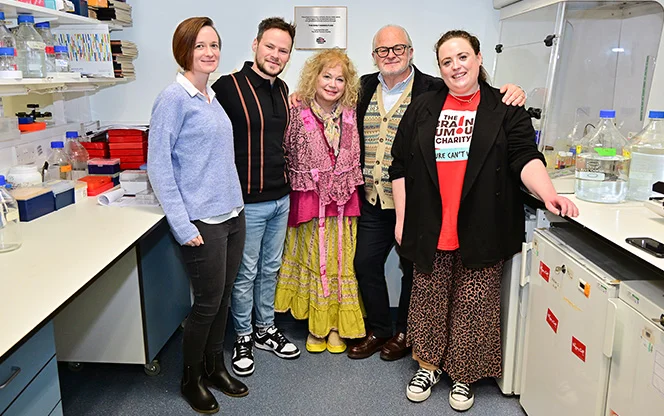 A family led partnership with The Brain Tumour Charity stands in a laboratory during a lab tour