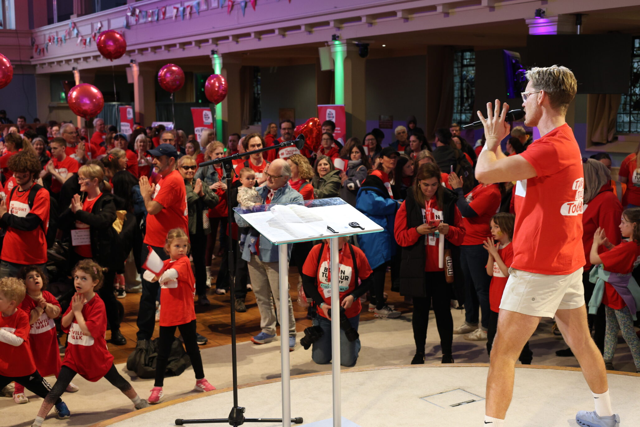 Rod Buchanan stands on stage at The Twilight Walk and leads a group of people in a warmup