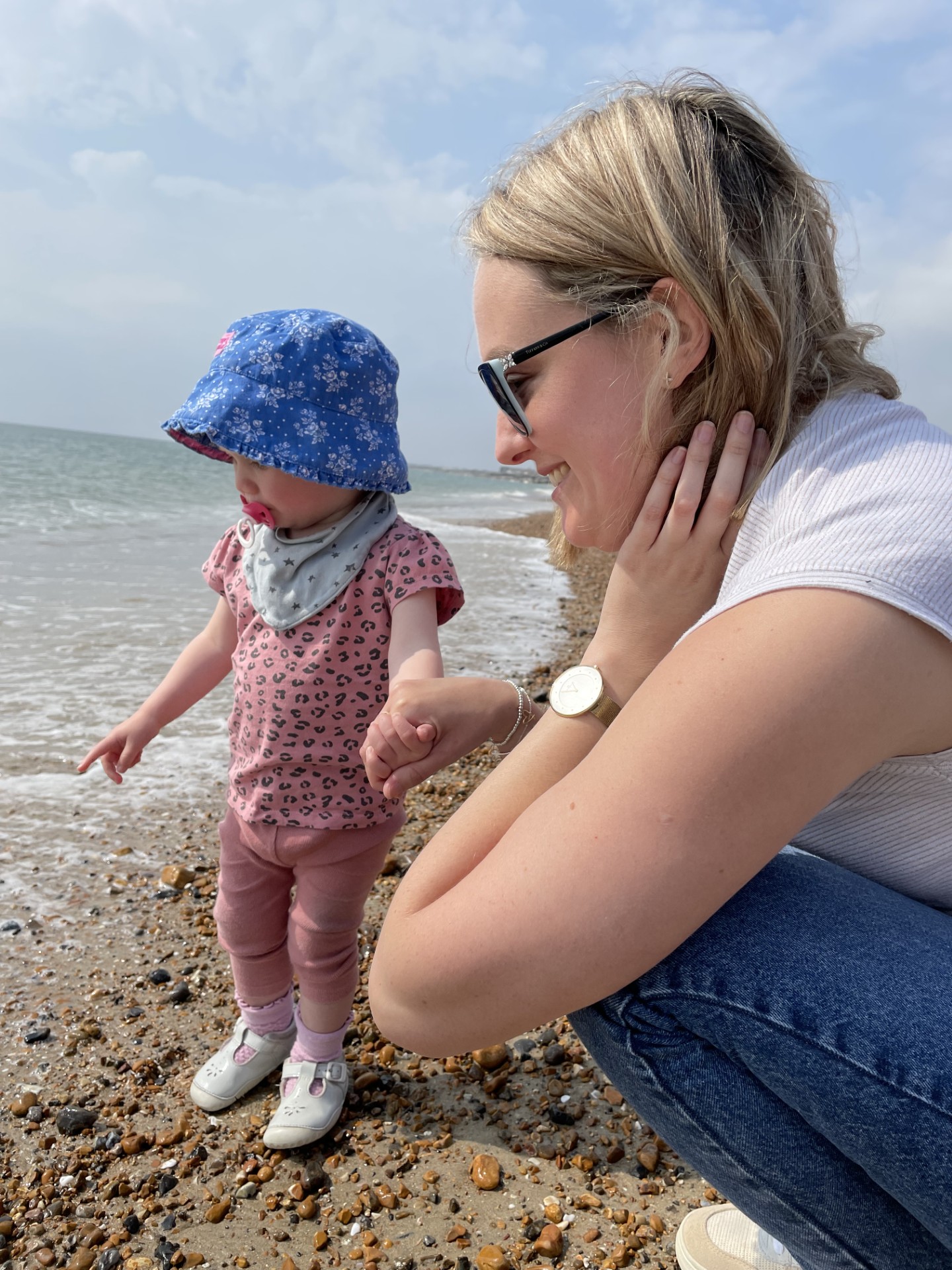 Laura Margott on the beach holding her young child's hand. Laura feels that voresidenib would greatly improve her quality of life.