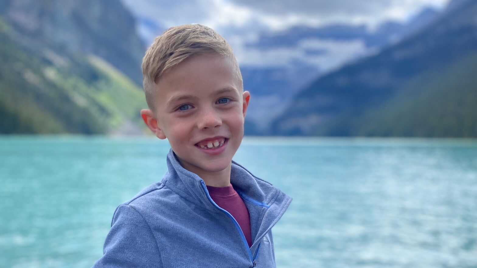 Oliver pictured in front of a turquoise see and mountains