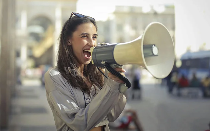 A woman speaking into a megaphone on a city street