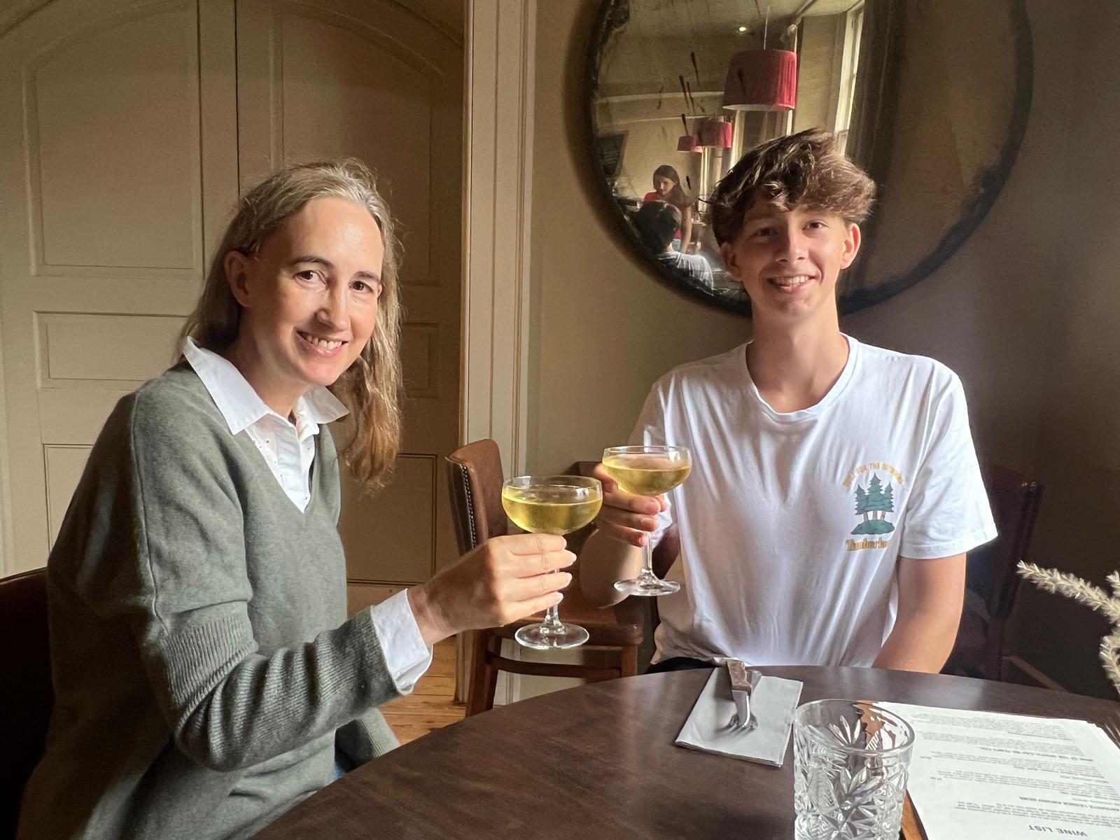 Sophie Kinsella and son, Oscar, cheers wine glasses at a table