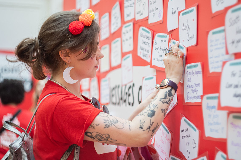 Grace Latter attaching a card to a wall full of messages of hope