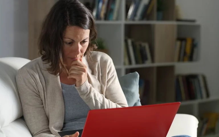 A woman sitting on a couch with a laptop on her lap, creating an advance care plan for her brain tumour diagnosis