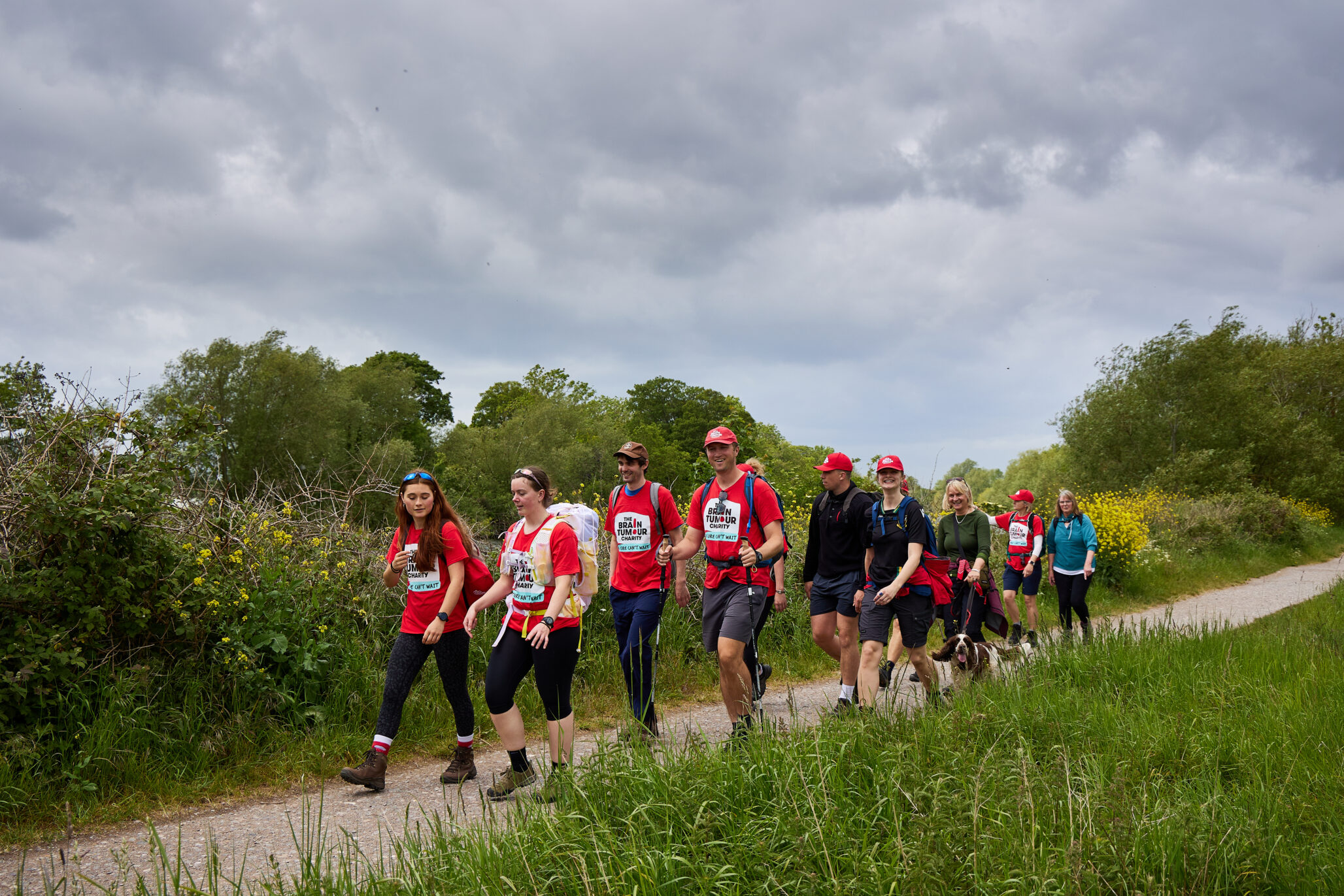 A group of walkers wearing red walk a scenic path surrounded by greenery