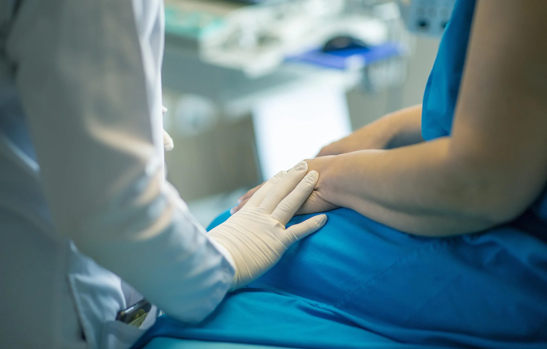 A medical professional resting their hand on a patient's hand and delivering some ACT-BT information