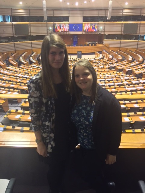 April and Emma stand in an auditorium