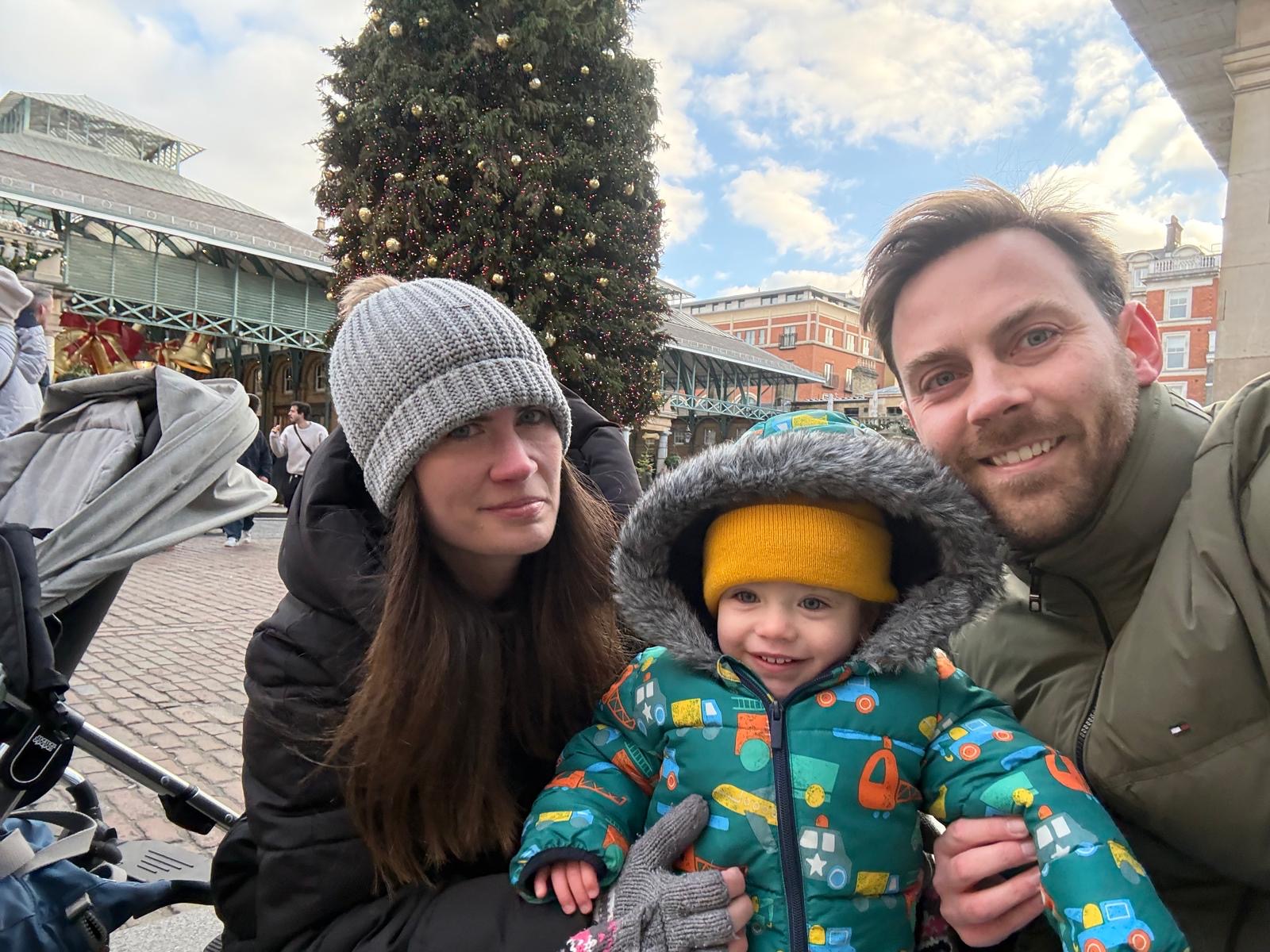Emma with her family in a square with a Christmas tree in the background