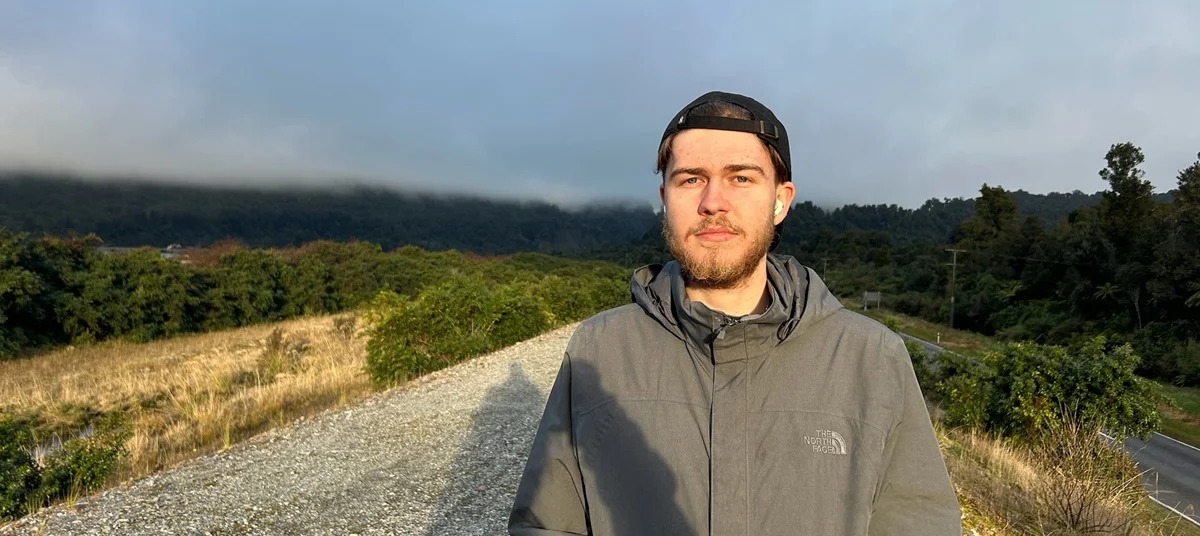 George Powell stands on a country road in a grey jacket